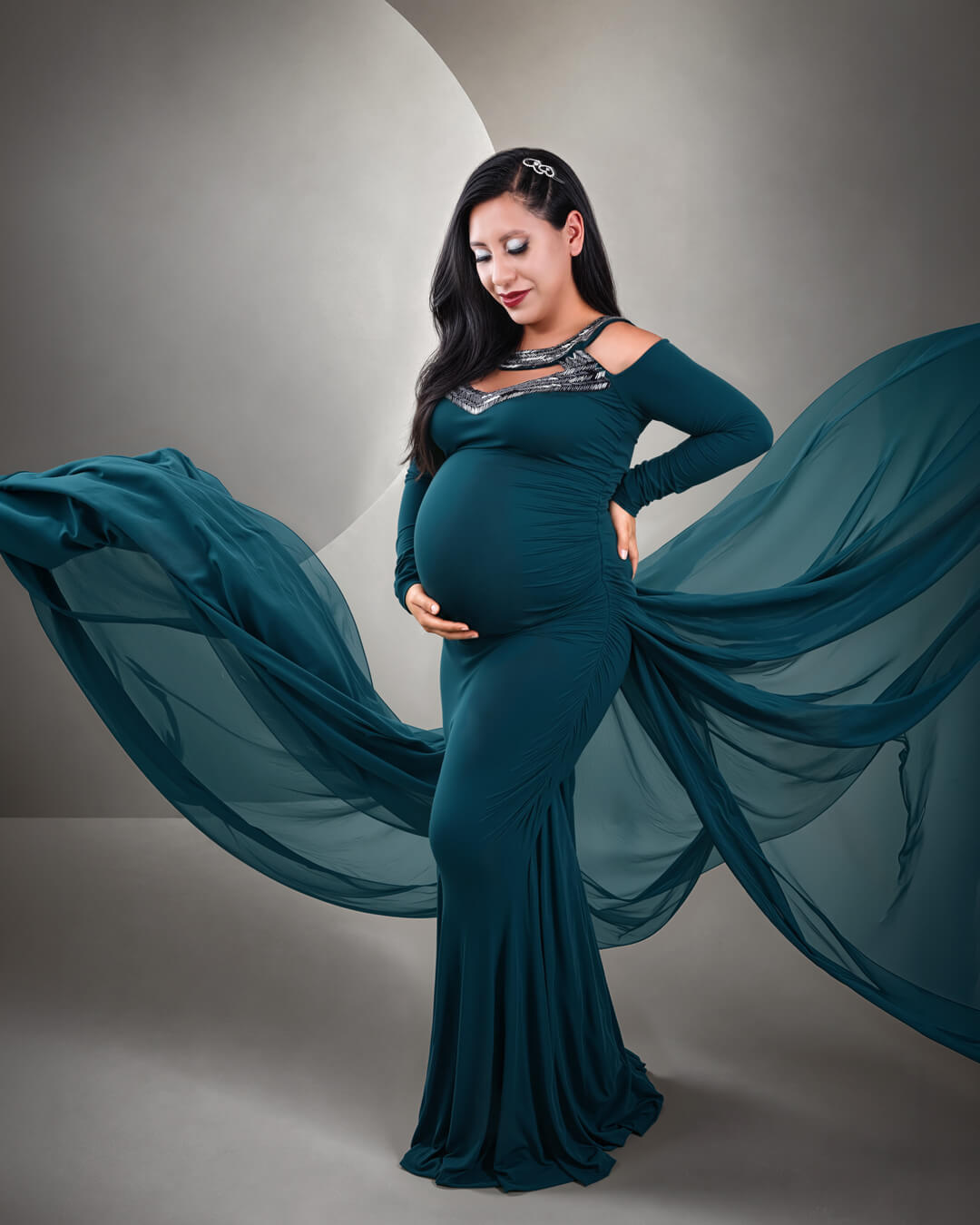Fotografía de embarazo en Cochabamba de una mujer embarazada posando con un elegante vestido negro largo y tela fluida. Sesión de maternidad y fotografía de composición en Cochabamba, Bolivia.